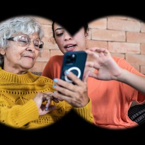 view from inside binoculars, from a spying point of view; woman and granddaughter using an iphone