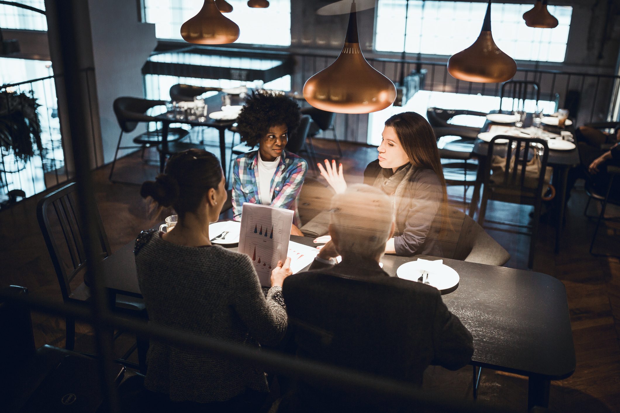 Businesswoman, creative team leader and her multi-ethnic team on the meeting in a high end restaurant