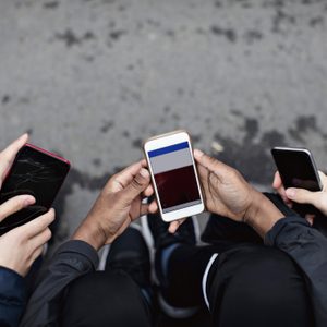 High angle view of friends using social media in mobile phone on street