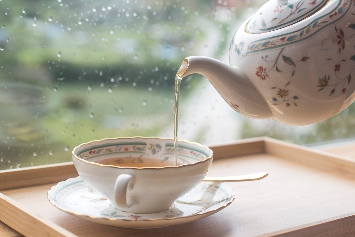 A man pouring black tea from the ceramic teapot in cafe. Close up on hands