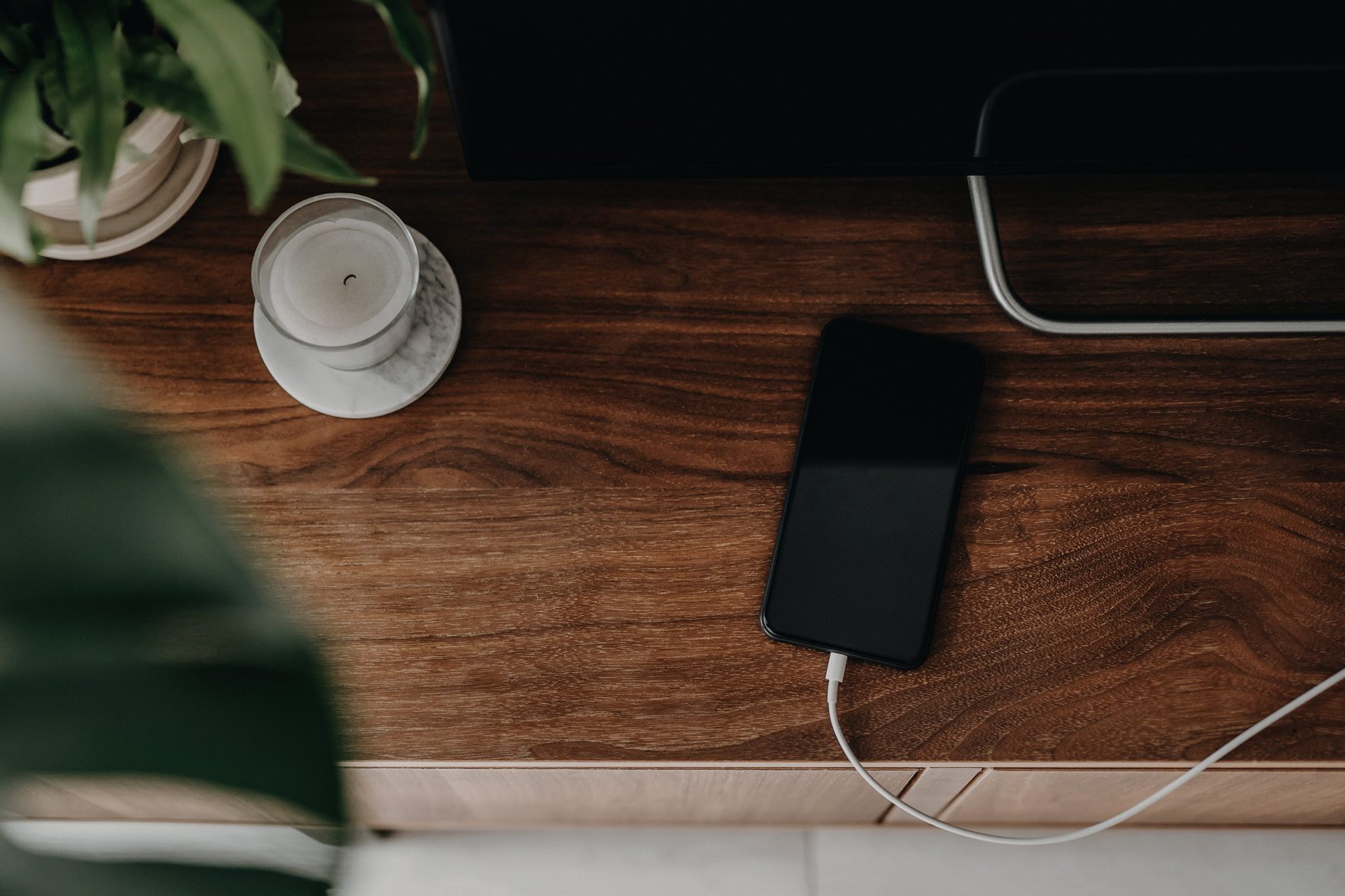 Directly above shot of a smartphone getting charged with power cable on a cabinet in the living room