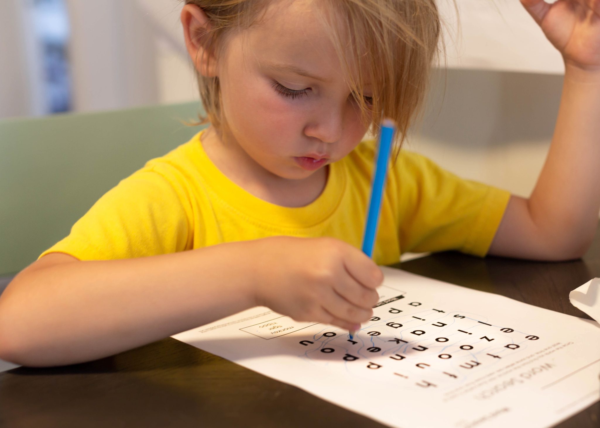 A young kid doing school work at home. Learning words.