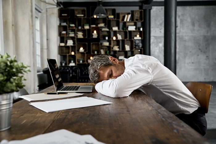 Mature businessman sleeping on desk in loft