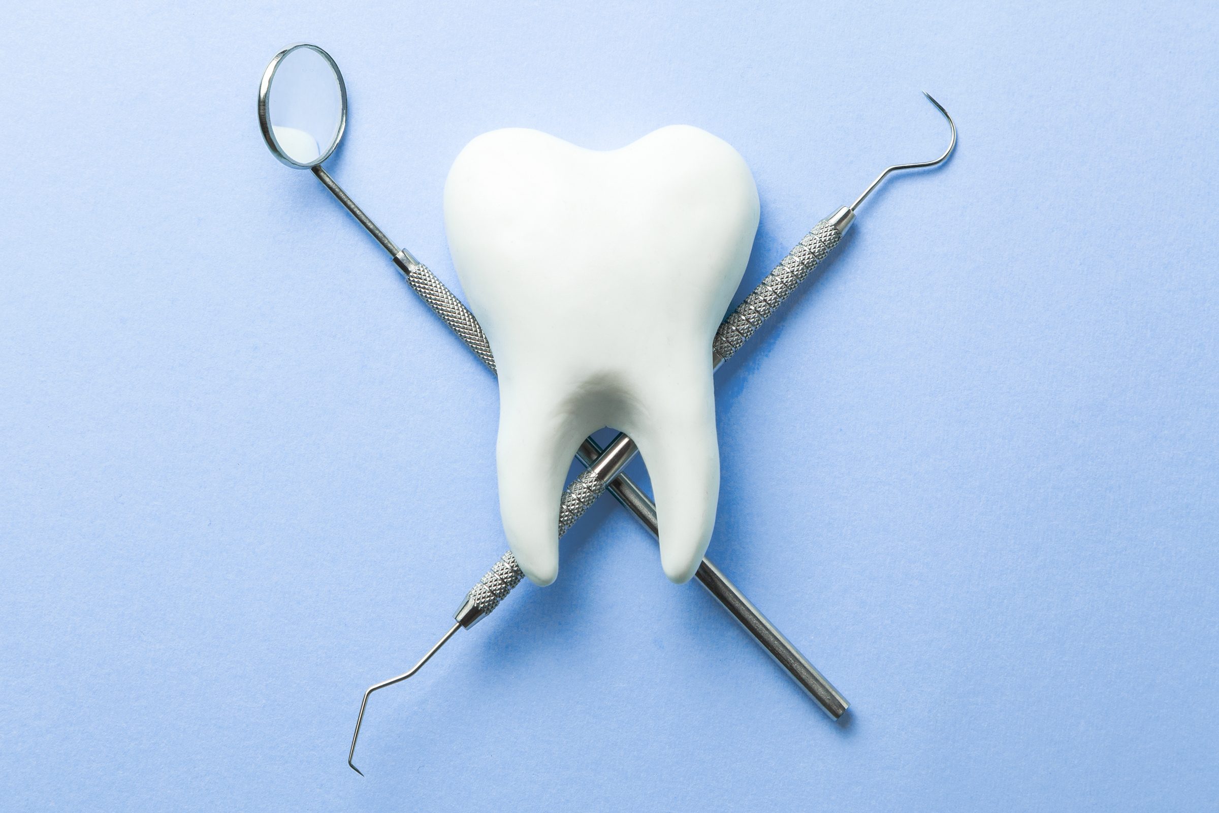 Tooth and dental instruments on blue background