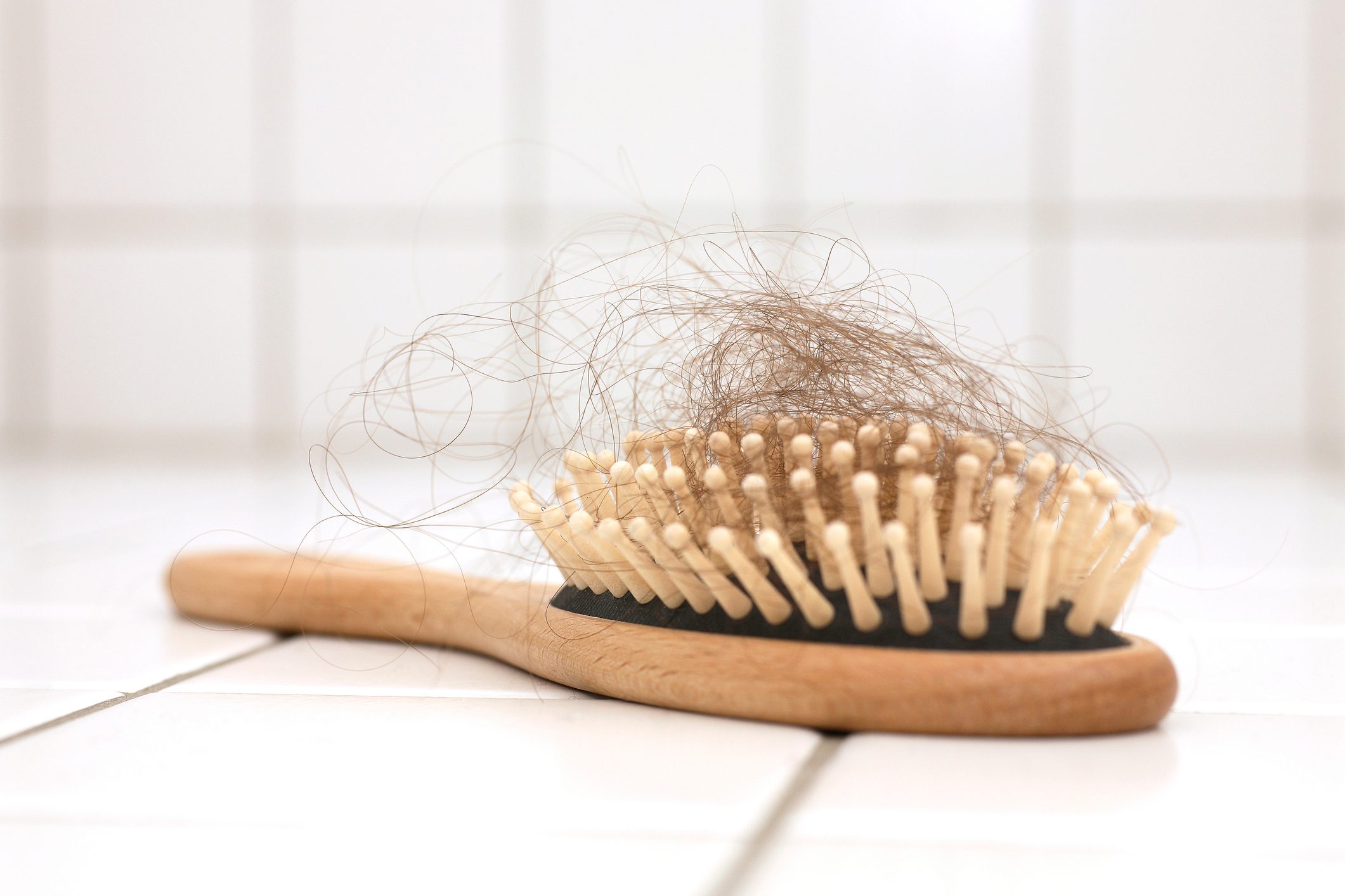Hair loss in hairbrush on white tiles