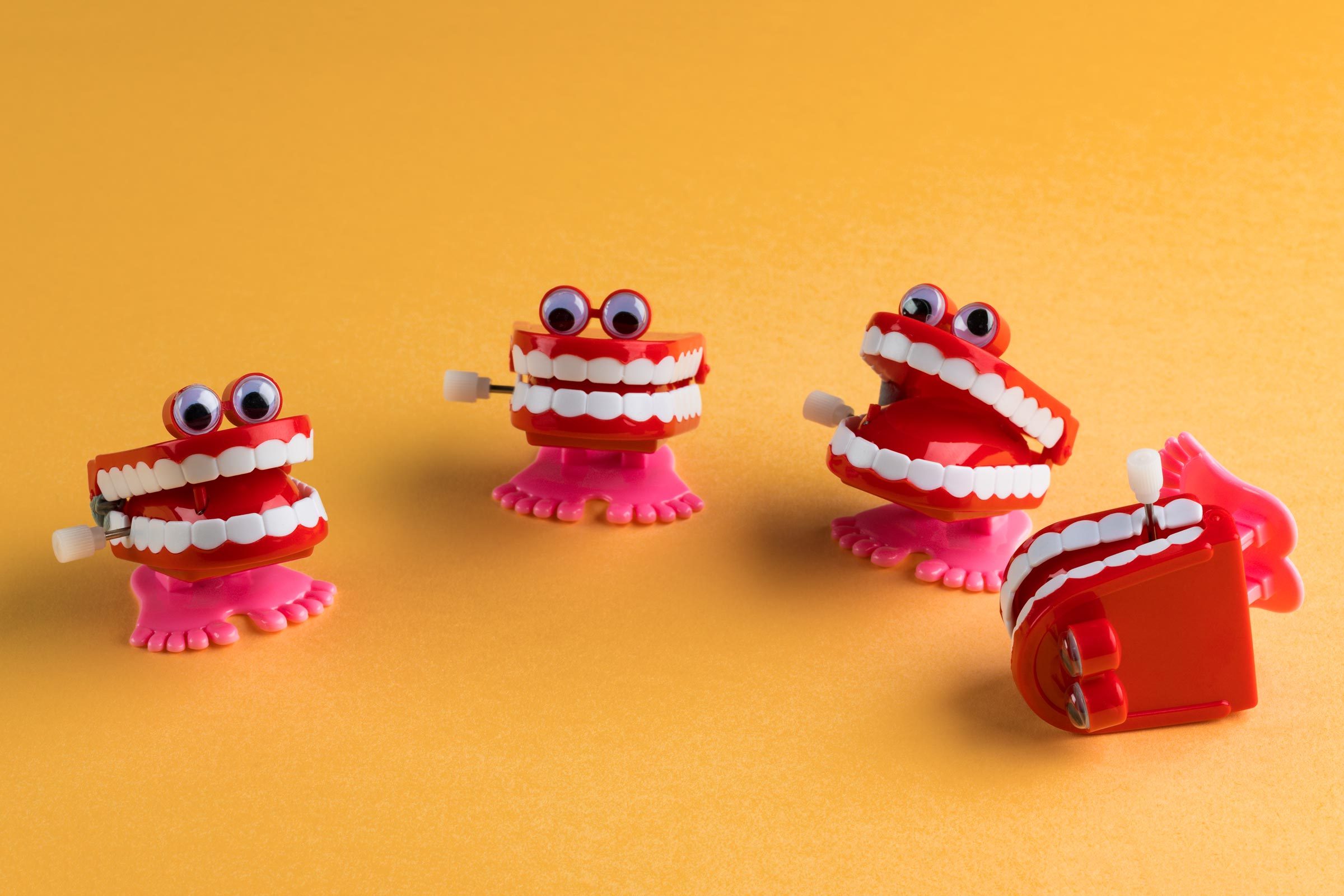 toy chatter teeth on a yellow background with one tipped over