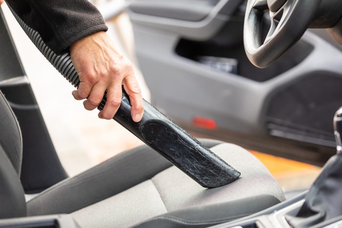 Cropped Hand Of Man Using Vacuum Cleaner In Car