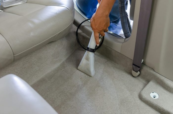 Midsection Of Man Cleaning Car With Vaccum Cleaner