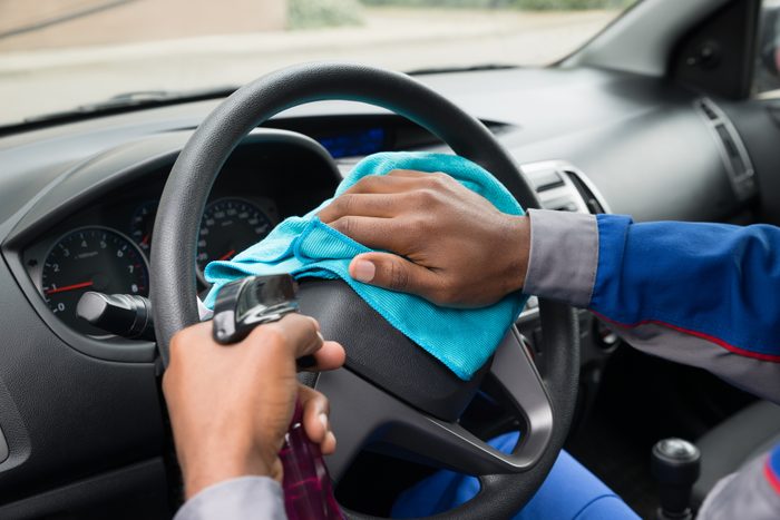 Worker Wiping Steering Wheel In Car