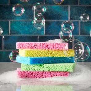 pile of colorful sponges on a kitchen counter with suds and bubbles