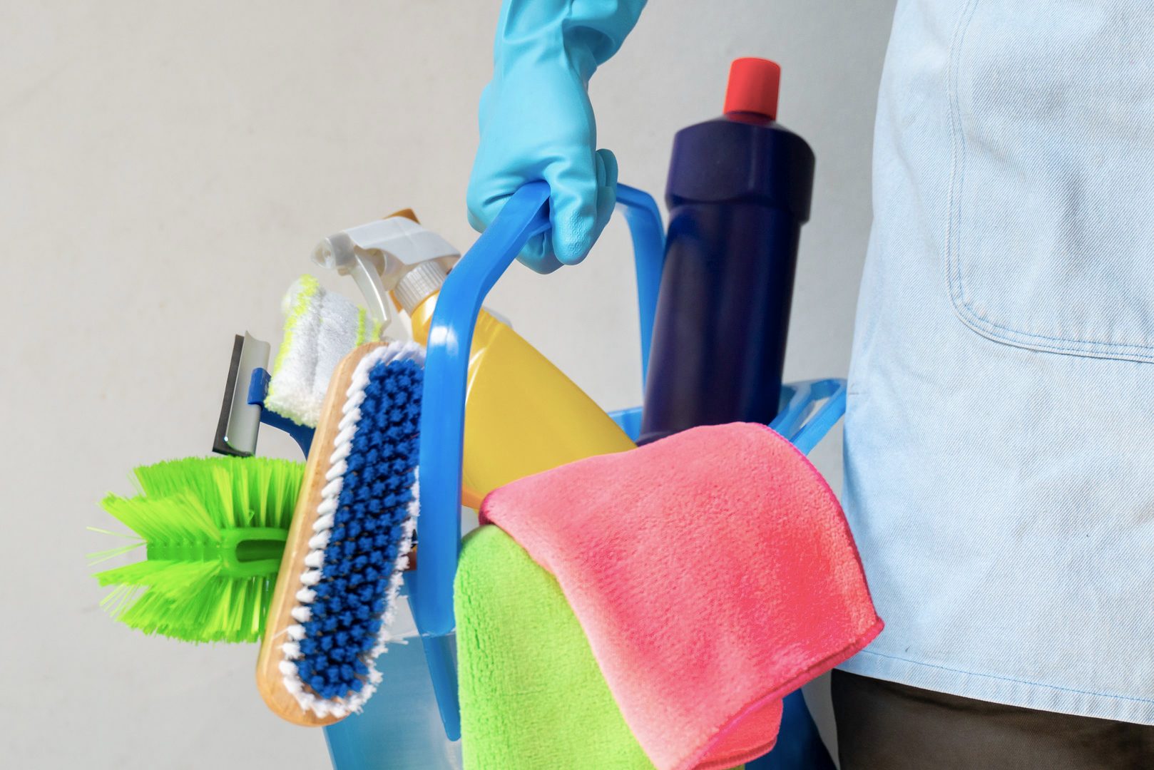 Man holding mop and plastic bucket with brushes, gloves and detergents in the kitchen