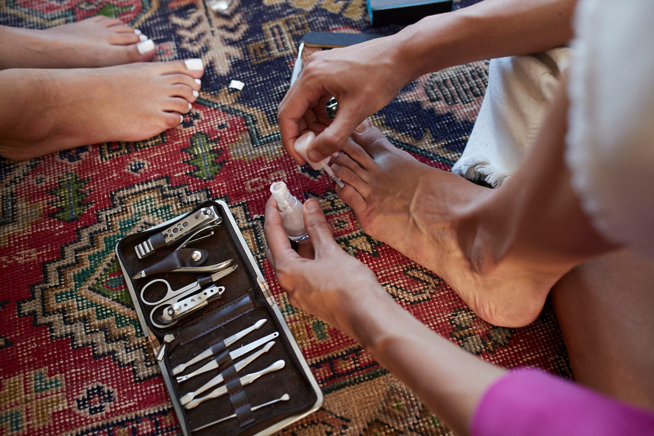Woman applying nail polish while sitting on carpet