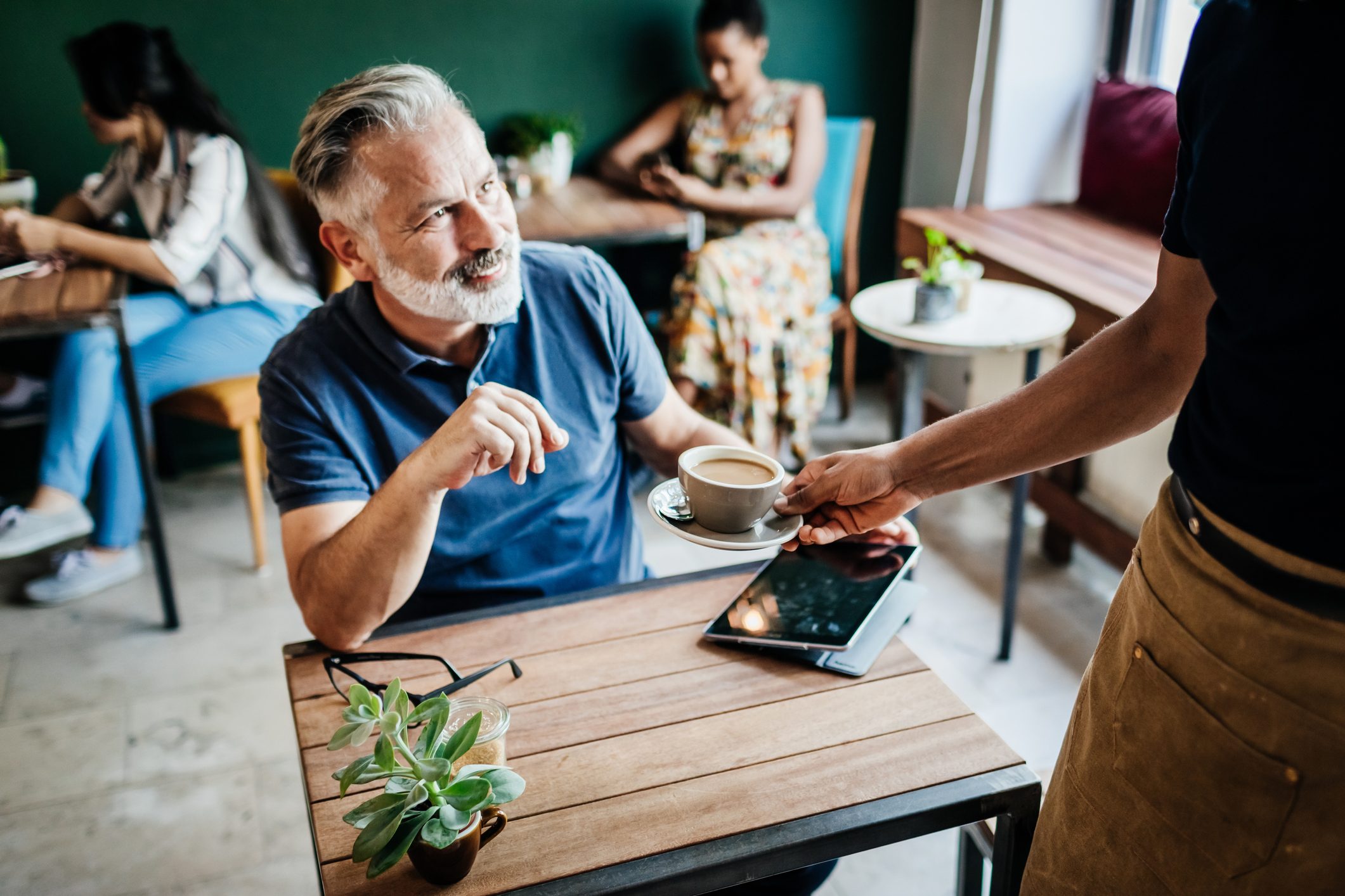 Barista Serving Mature Man Cup Of Coffee