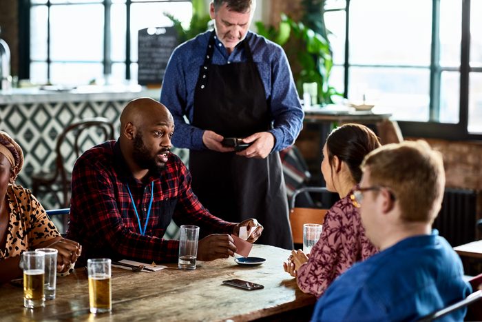 Small business owner taking payment from work colleagues