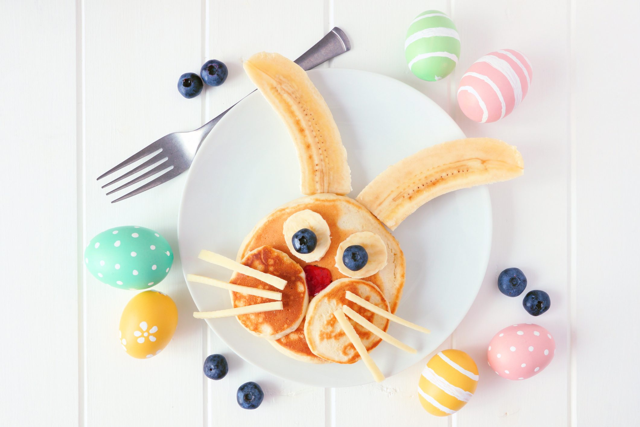 Cute Easter Bunny pancakes on a white plate, top view over white wood