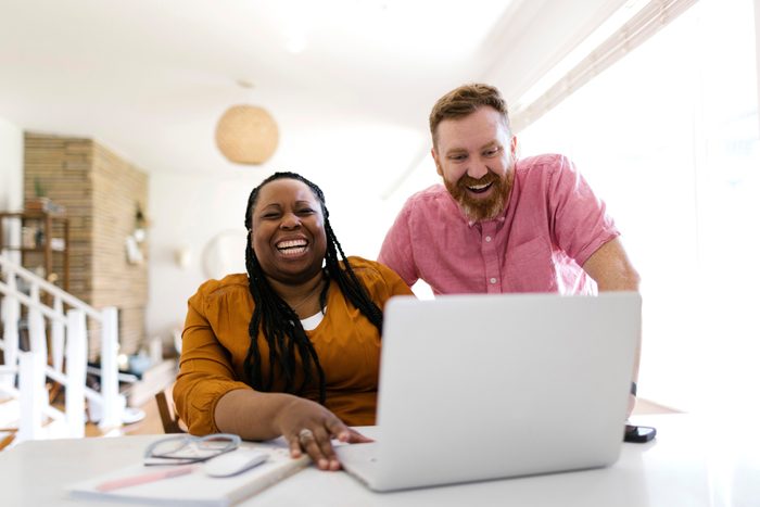 Man and woman looking at laptop at desk in home office