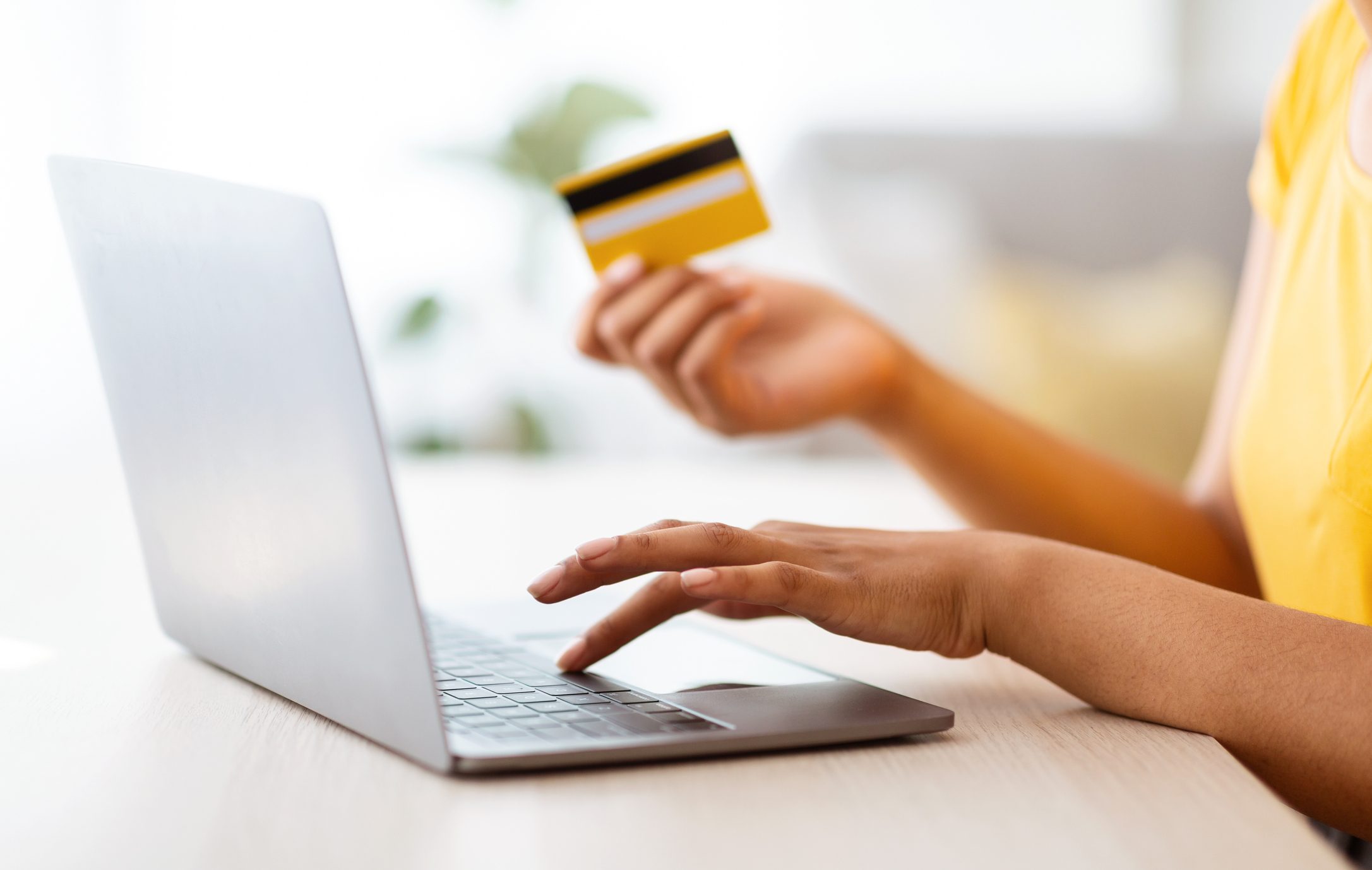 Black woman using laptop and credit card sitting at desk