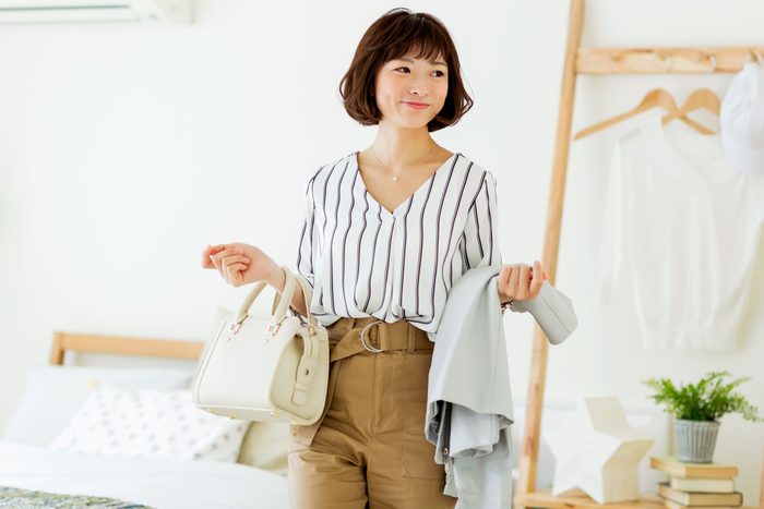 woman getting dressed for the day carrying her purse and a jacket
