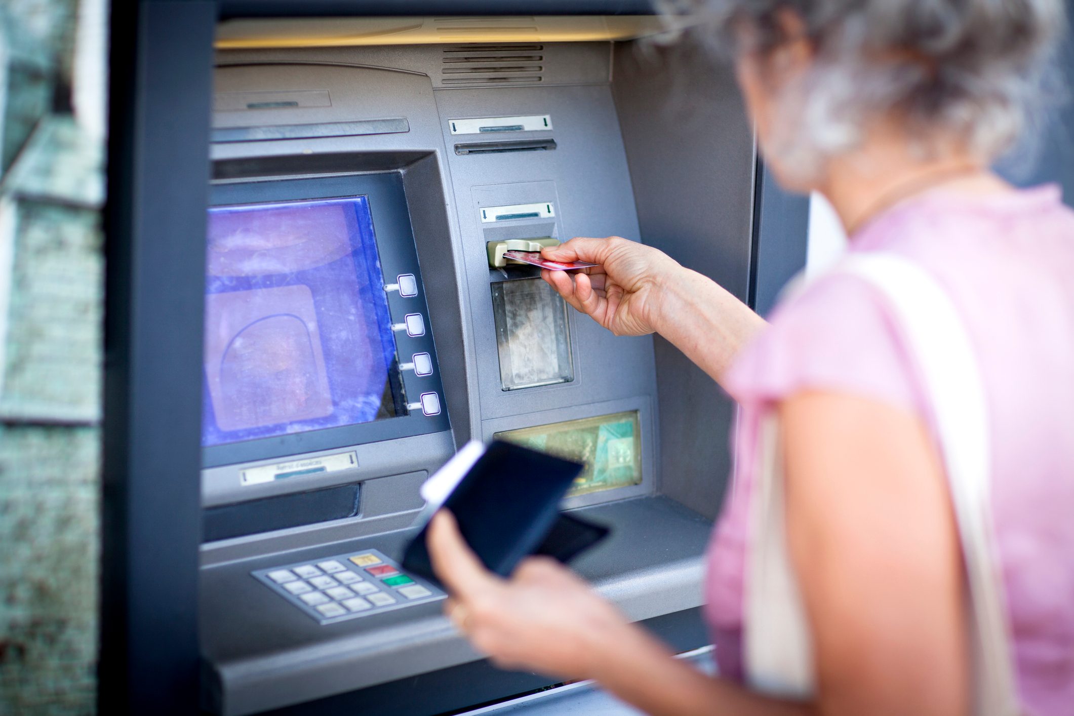 Mature woman inserting credit card into local french cash machine