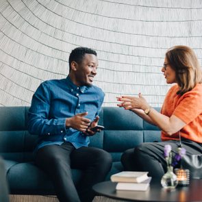 Businessman and woman using mobile phones while sitting on couch during conference