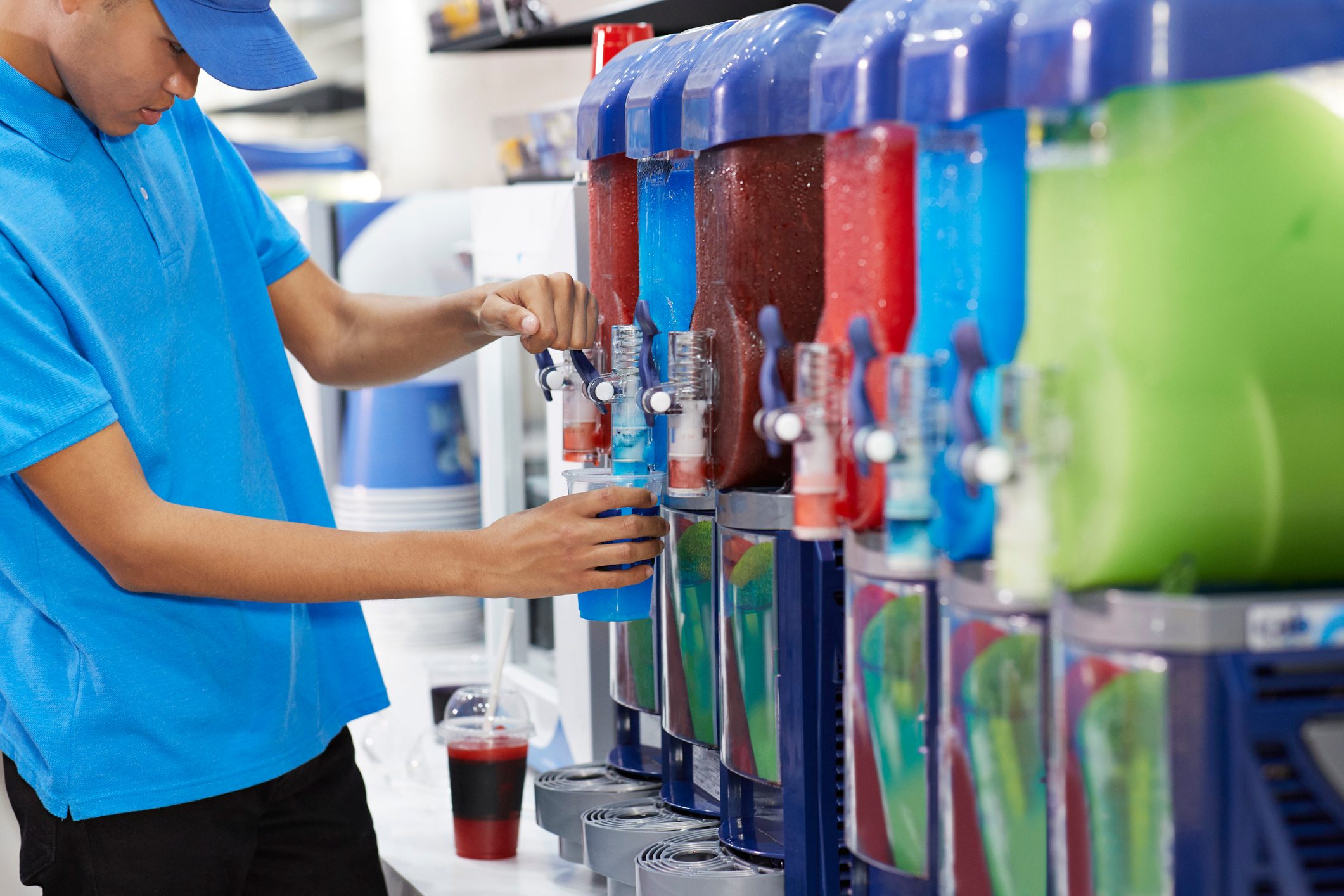 Male employee filling soda in cup from machinery