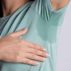 Close-up asian woman with hyperhidrosis sweating. Young asia woman with sweat stain on her clothes against grey background. Healthcare concept.