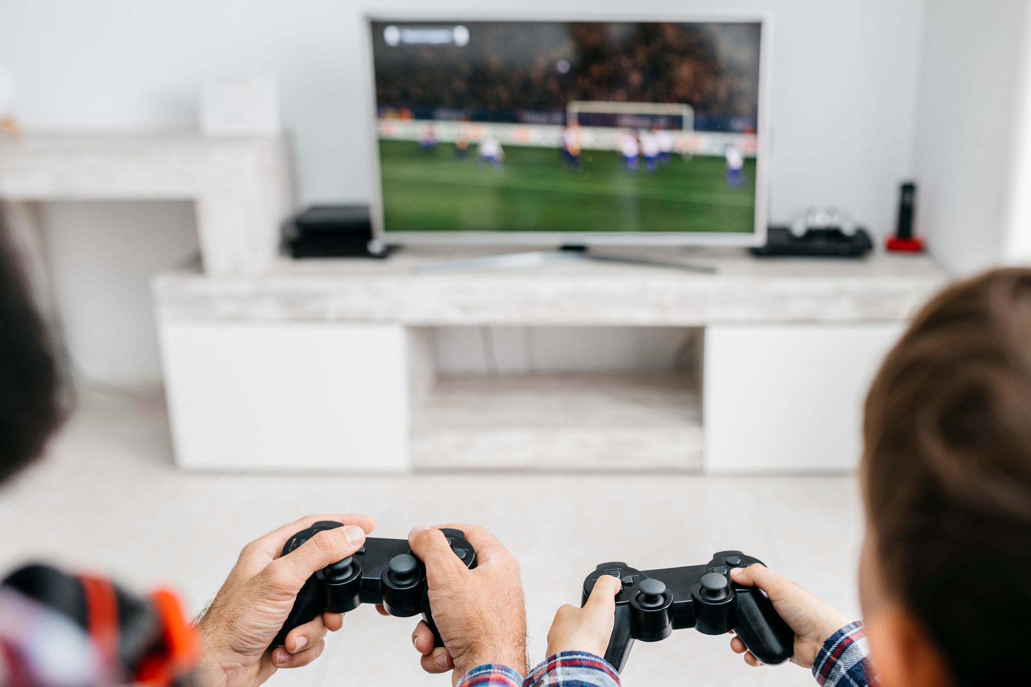 Father and son playing computer game together at home, partial view
