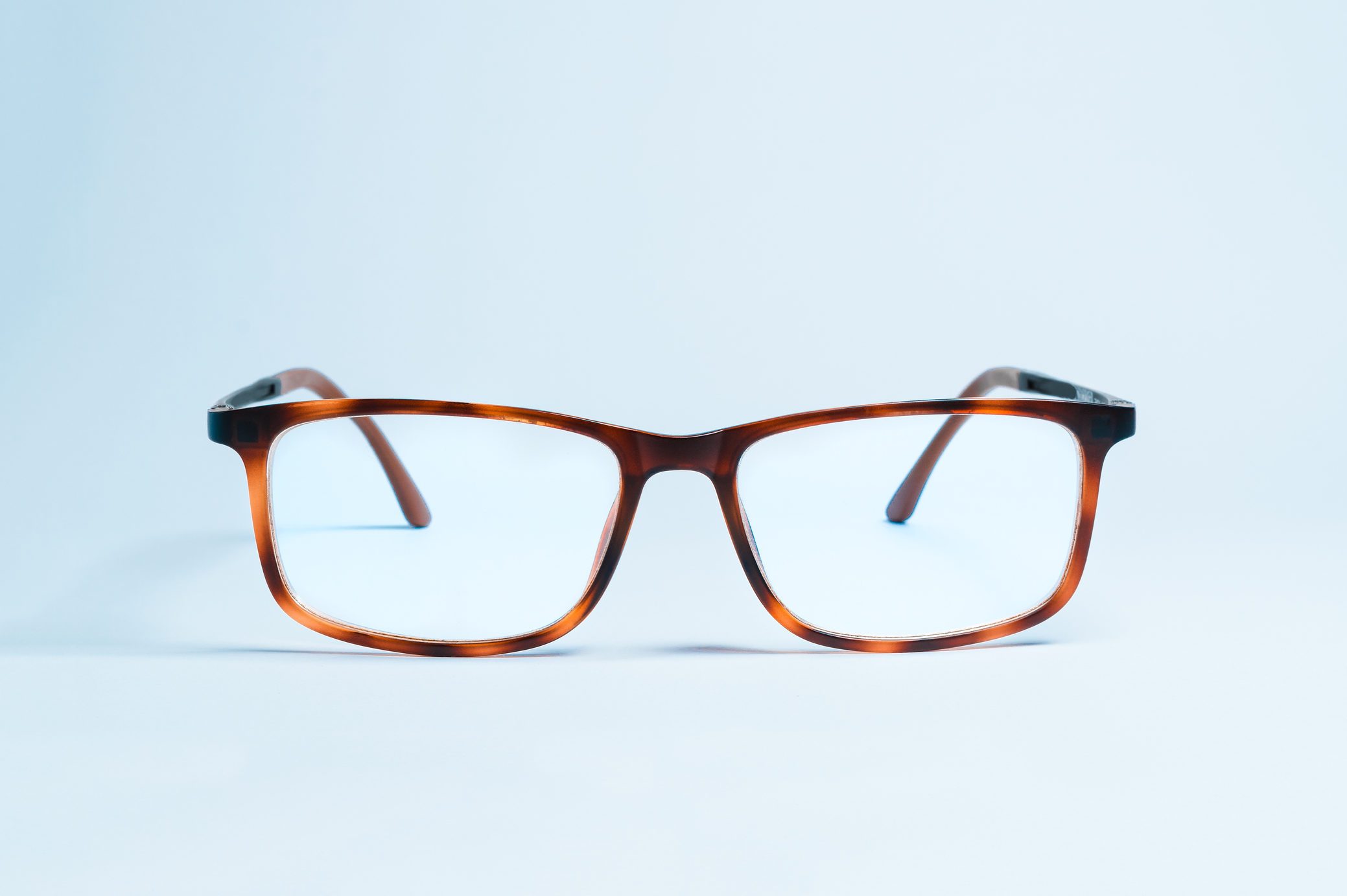 Close-Up Of Eyeglasses Against Blue Background