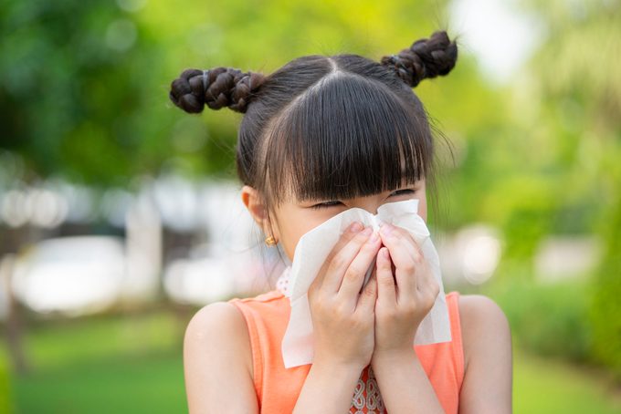 Small girl blowing her nose into a napkin