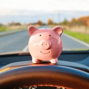 piggy bank sitting on the dashboard of a car on a road trip