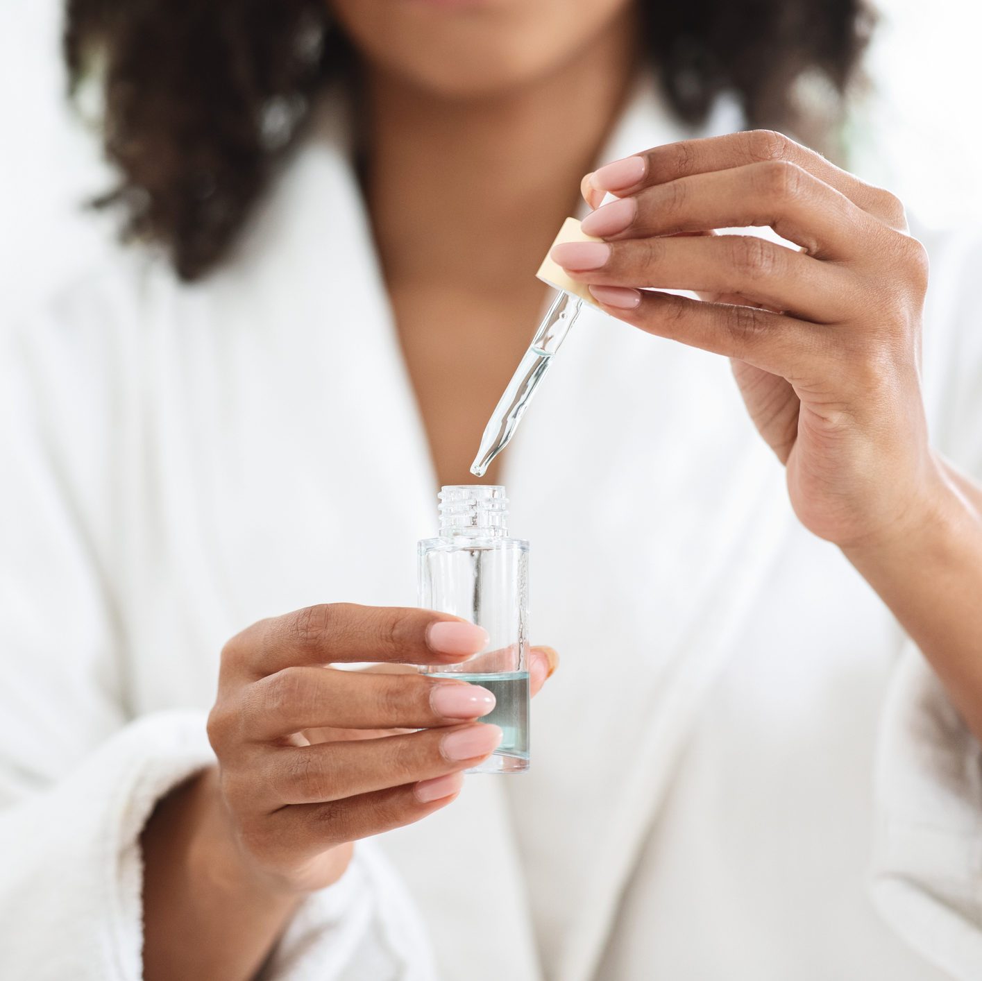 Essential Oils Benefits. Bottle With Organic Serum In Hands Of Black Woman