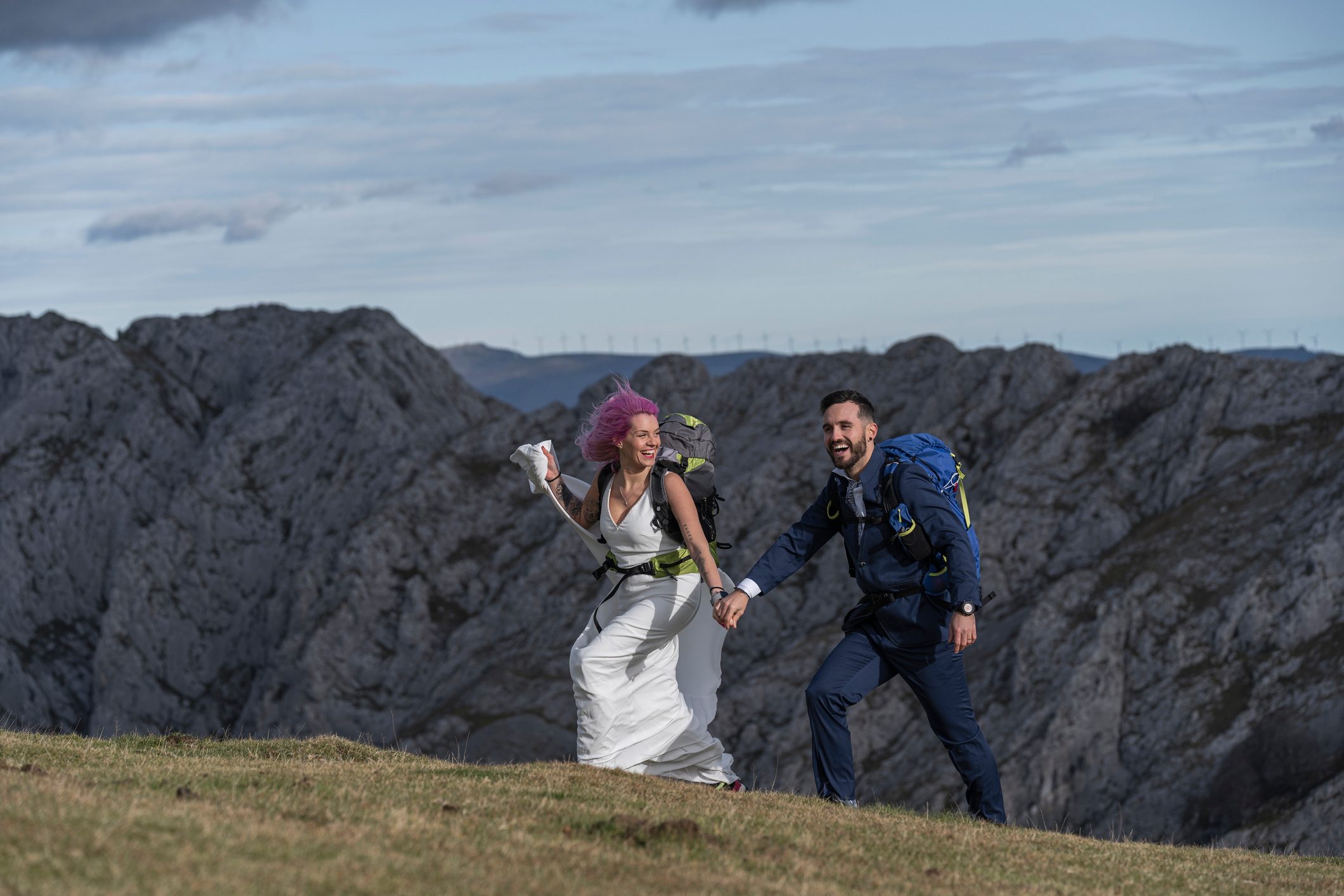 Bridal couple with climbing backpacks walking on meadow