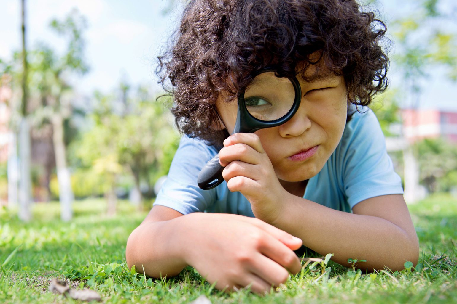 Little boy with magnifying glass in park