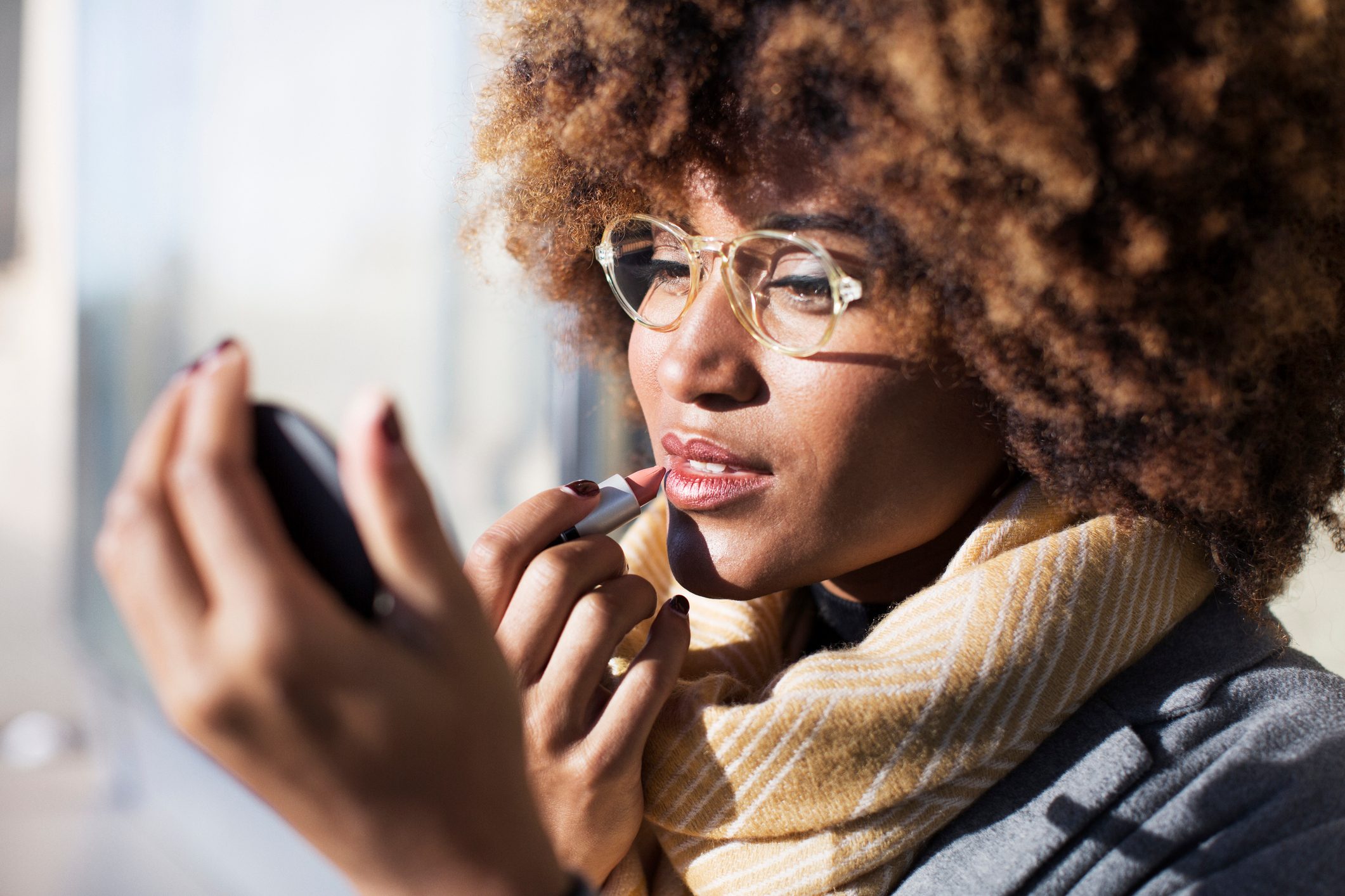 Close-up of woman applying lipstick at bus stop