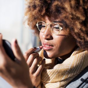 Close-up of woman applying lipstick at bus stop