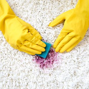 rubber gloves cleaning red stain from white carpet