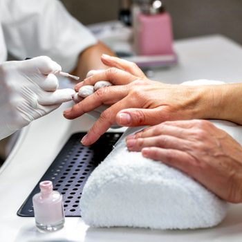 Nail technician with latex gloves painting fingernails