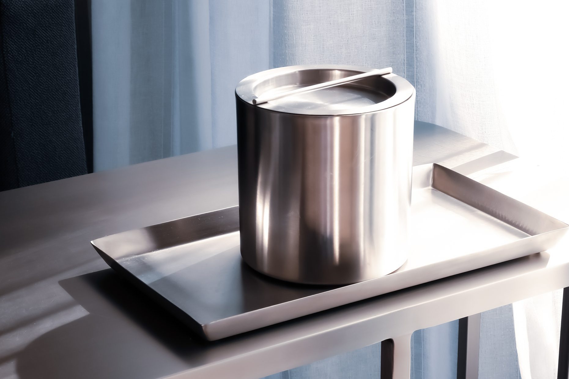 Silver stainless steel ice bucket and tray in hotel room.