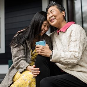 Adult woman and senior mother talking on front porch