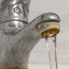 Old Bathroom Sink Faucet contaminated with calcium and grime. Hard water flows from an old tap aerator.