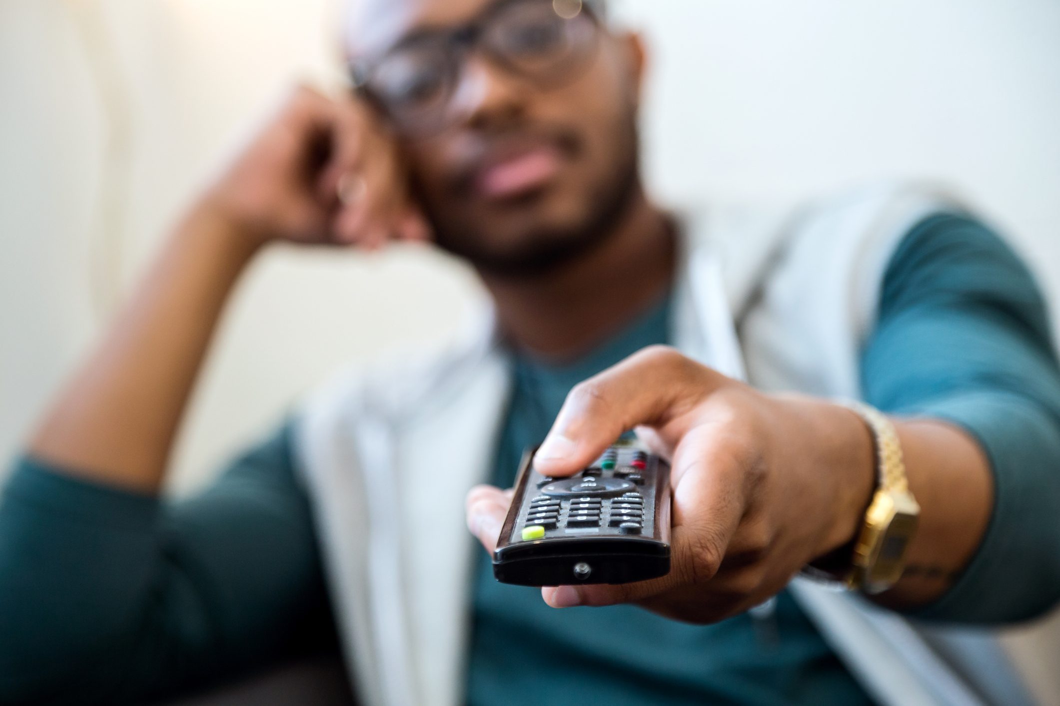 Handsome young black man watching tv at home.