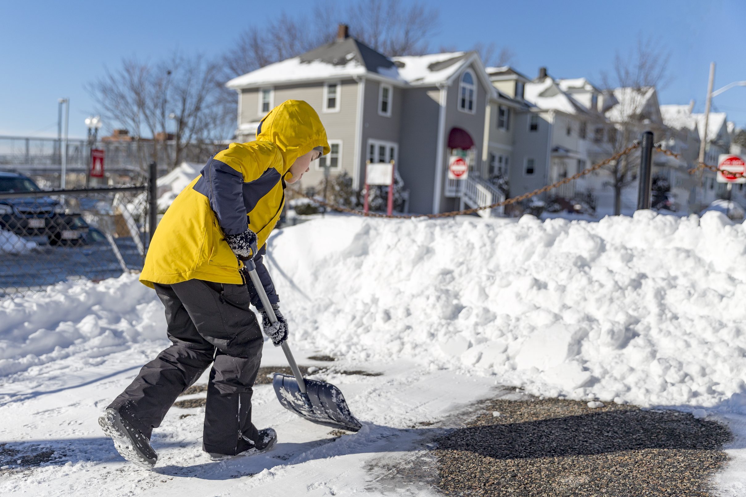 child cleans snow in the yard