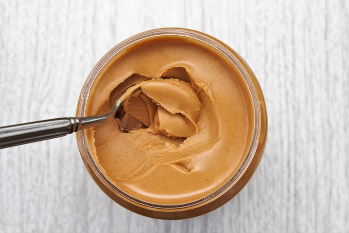 Peanut butter on spoon in jar