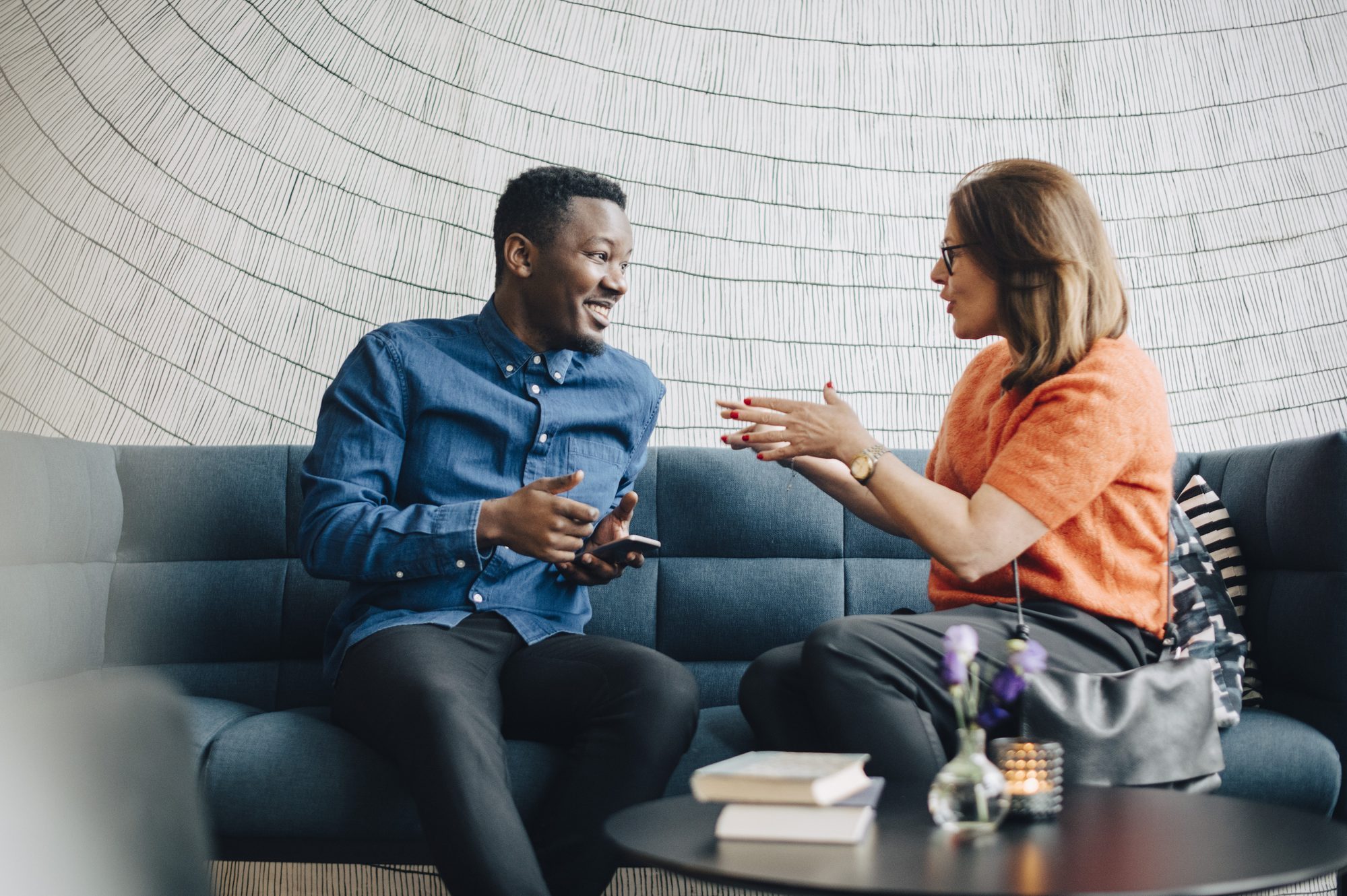 Businessman and woman using mobile phones while sitting on couch during conference