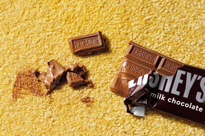 melted chocolate bar creating a chocolate stain on a yellow carpet