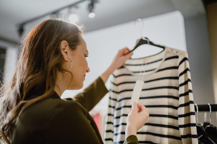Young woman looking in to price tag in the clothing store