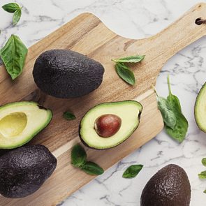 Ripe avocados cut in half on a wooden cutting board