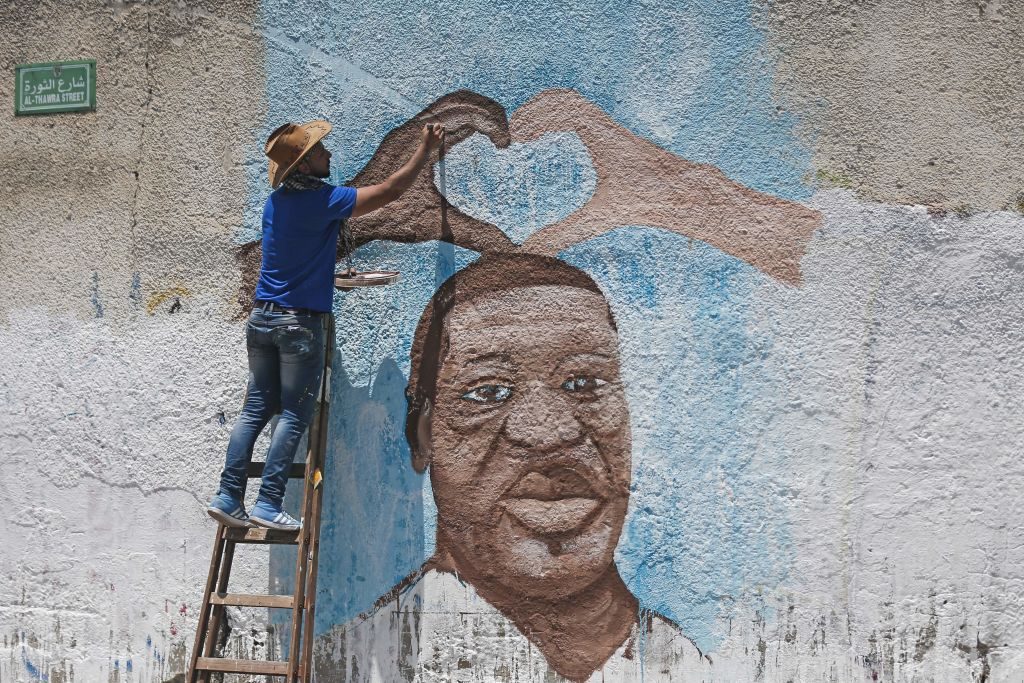 Palestinian artist Ayman al-Housari paints a mural depicting George Floyd in Gaza City on June 16, 2020.