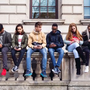 gen z people sitting on a wall and texting