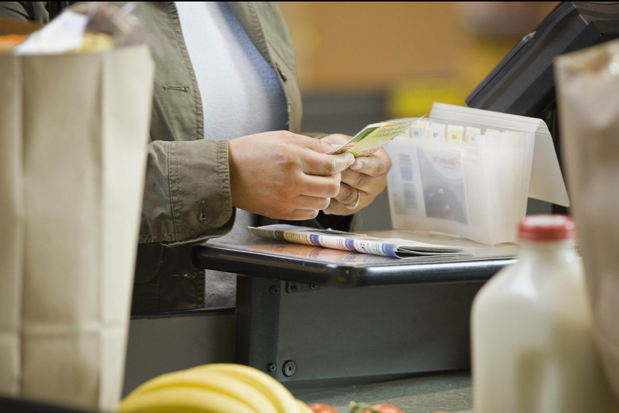 Woman sorting coupons at supermarket, close-up, mid section